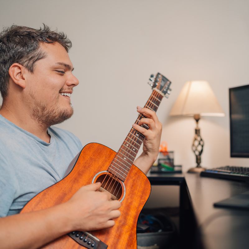 Musician playing guitar at home